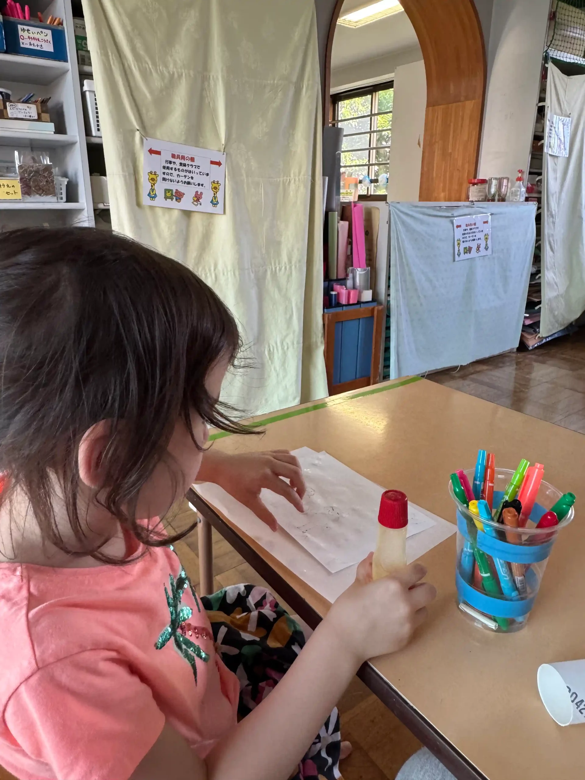 Enfant de 5 ans concentrée sur son collage dans la salle de bricolage d'une 児童館