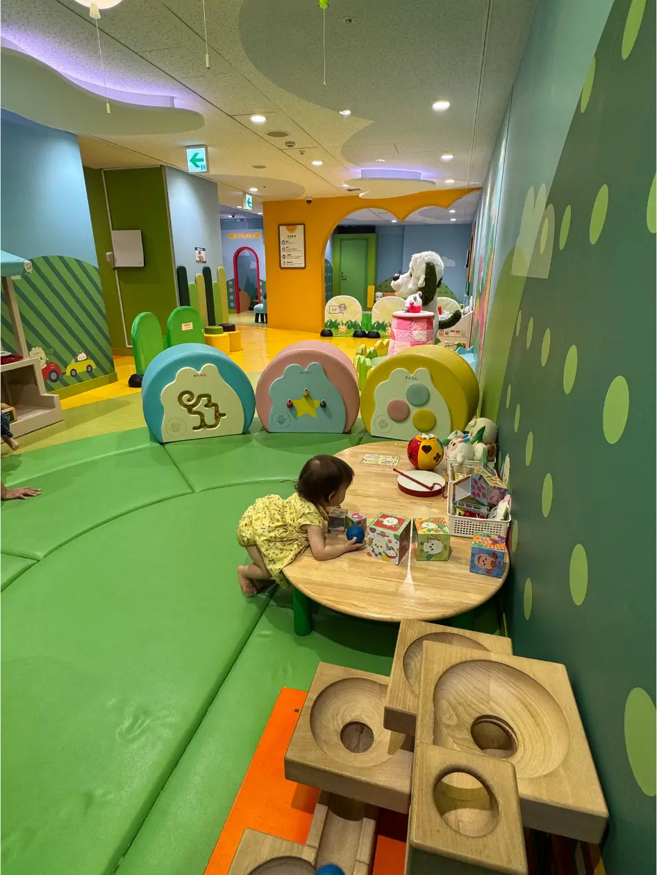 Bébé jouant dans l'espace bébé de Nicohapikids à Ikebukuro, sol vert mousse, jouets en bois et personnages NHK