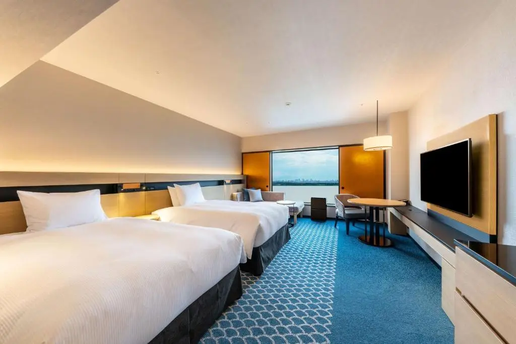 Chambre spacieuse du Hilton Tokyo Bay avec plusieurs lits et vue sur la baie de Tokyo, hôtel familial près de Disney