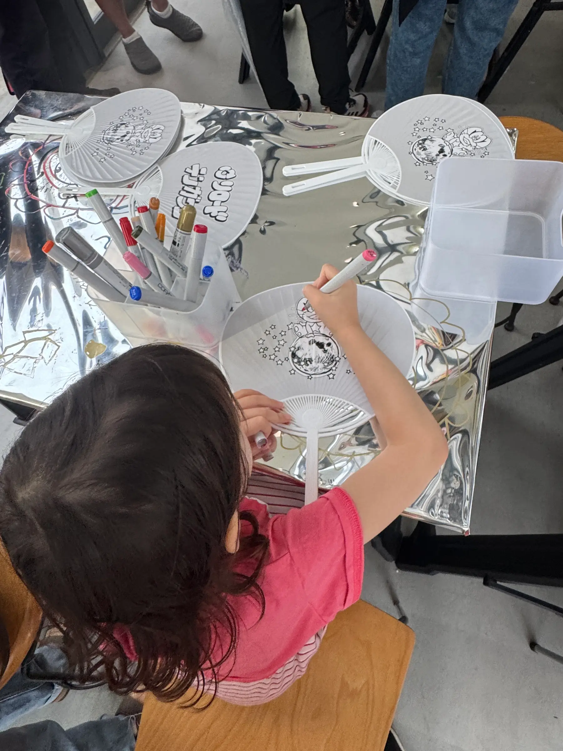 Enfant en train de colorier un uchiwa au design du street artiste TENGAone lors de l atelier Moon Art Night Shimokitazawa 2026