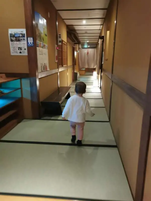Enfant marchant pieds nus dans un couloir entièrement recouvert de tatami au ryokan Saikatei Jidaiya à Yamagata