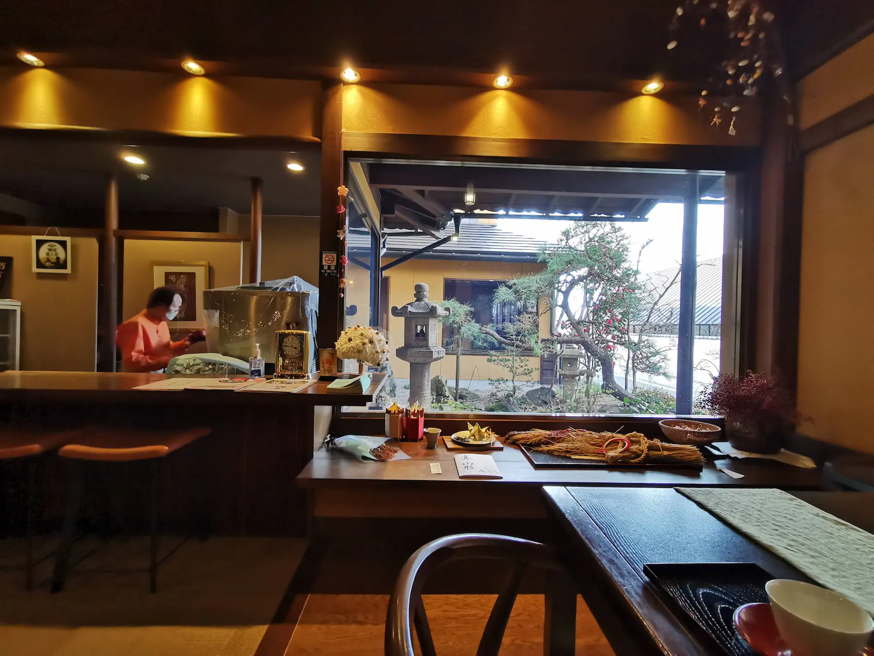 Salon d'accueil du ryokan Saikatei Jidaiya à Yamagata, grande baie vitrée donnant sur un jardin japonais avec lanterne en pierre, pin et camélias
