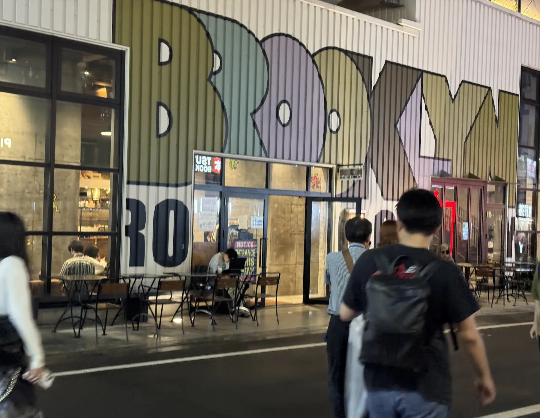 Façade du Brooklyn Roasting Company à Shimokitazawa avec grande fresque murale en lettres vert olive et rose sur fond blanc
