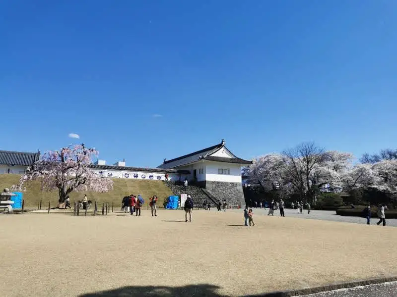 Esplanade du château de Yamagata au printemps, tourelle blanche, cerisier pleureur et visiteurs pendant le hanami